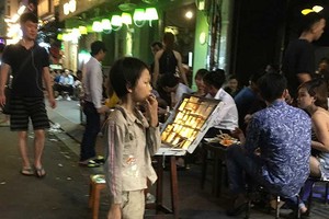 在裴援街上，一名小孩拿著汽油瓶讓母親作噴火表演。