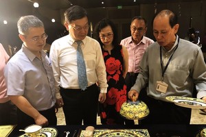 李玉明先生(右一)向到訪賓客介紹 2017年越南舉辦亞太經合會議國宴上明隆一生產的餐具。