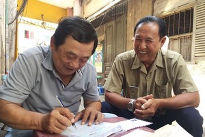 福大叔（左）幫助街坊填寫申報表。