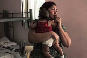 一位移民母親與孩子在庇護所中。 (圖源：AP)