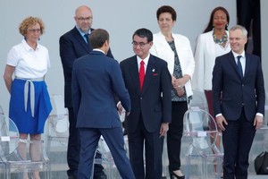 法國總統馬克龍與前來出席國慶閱兵儀式的日本外務大臣河野太郎（前排中）握手。（圖源：路透社）