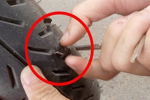 撒釘弊端“死灰復燃”。圖為在守德郡1A號國道路段上扎到釘子的摩托車車輪。