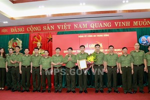 公安部副部長裴文南向阮明政少將頒授網絡安全與高科技罪犯防治警察局黨部成立《決定》並贈送鮮花祝賀後與該黨部成員合影留念。（圖源：公安部）