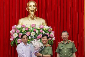 中央組織部長范明政（左）向公安部副部長阮文山中將（中）送鮮花表示祝賀。（圖源：春春）