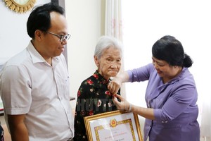 第七郡委常務副書記杜氏草代表郡委常務處向老前輩黨員頒授黨齡紀念章。（圖源：市黨部新聞網）