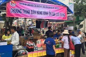 勞工在流動攤位選購平抑物價商品。