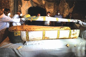 11月24日，在埃及盧克索省，工作人員在墓室內打開一口裝有木乃伊的棺材。（圖源：互聯網）
