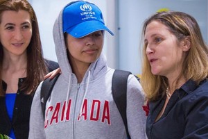 拉哈芙(中)身著寫有“加拿大”字樣的灰色運動帽衫、頭戴印有聯合國難民署標誌的棒球帽步出機場。（圖源：AFP）