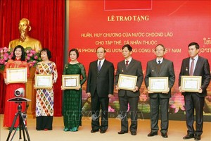 老撾新聞文化與旅遊部部長波顯坎‧馮達拉同志（中）頒發獎狀並合照。（圖源：越通社）