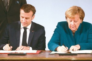德國總理默克爾（右）和法國總統馬克龍（左）當地時間22日在德國西部城市亞琛簽署《德國和法國關於合作和一體化的條約》(《亞琛條約》)。（圖源：AFP）