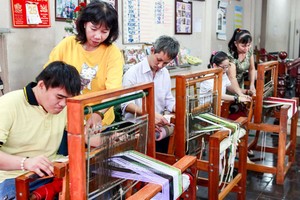 阮氏清水老師（左二）和胡氏金釵老師（右邊）在給學員們指導紡織方法。