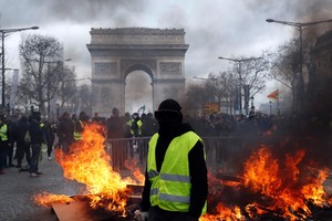 黃背心示威者站在凱旋門和被焚燒雜物前面。（圖源：AP）