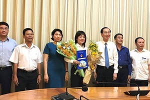 新任第八郡人委會副主席阮氏秋花同志（中）接過人事調動、批准《決定》和鮮花祝賀後與市領導合照。（圖源：孟和）