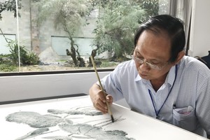 張漢明在瓷板上繪畫。 