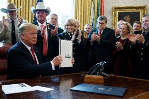 3月15日，美國總統特朗普否決一項國會決議，該決議叫停止他此前宣布的美國南部邊境出現“國家緊急狀態”。圖為特朗普（前）在華盛頓白宮展示否決令。這是特朗普在其任內首次行使否決權。（圖源：新華社/AP）