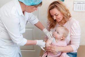 一位母親正抱著嬰兒接種疫苗。（圖源：UNICEF）