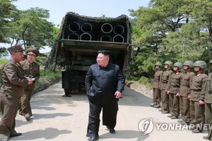 圖為朝鮮國務委員會委員長金正恩（居中）以300毫米口徑放射砲為背景向朝軍官兵下達指示。（圖源：韓聯社）