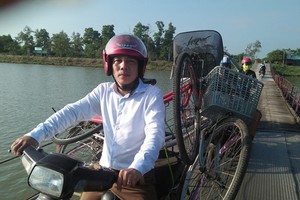 黃友喬老師用摩托車載自行車騎過廣治省趙峰縣趙度浮橋，以給該地學生們贈送車子。