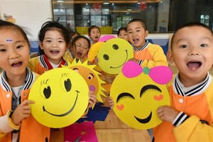 一家幼稚園的孩子在展示笑臉卡。（圖源：新華社）