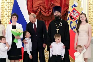 普京微笑著和受表彰的家庭合影。（圖源：Sputnik）