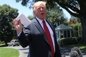 特朗普11日在白宮外草坪向記者揮舞類似信件的紙片，稱收到金正恩來信。（圖源：路透社）