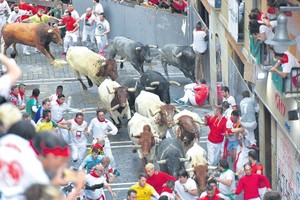 參加奔牛節的觀眾躲避牛群衝撞。（圖源：AFP）