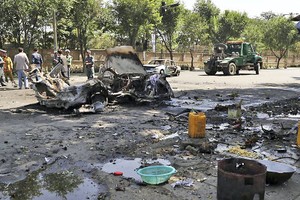 爆炸造成重大人員傷亡，校門附近商販的攤位嚴重受損，至少兩輛汽車被毀。（圖源：AP）