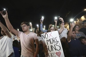 民眾在美墨邊境用手機照明守夜呼籲控槍。（圖源：AP）