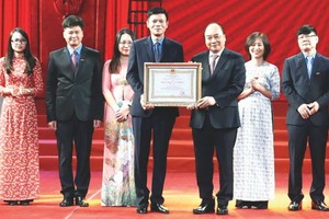 政府總理阮春福（前右）向《勞動報》總編輯阮玉顯頒授三等勞動勳章。（圖源：越通社）