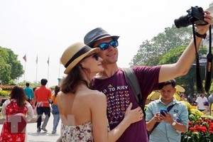 一對外籍情侶遊客在阮慧步行街上自拍紀念照。（圖源：越通社）