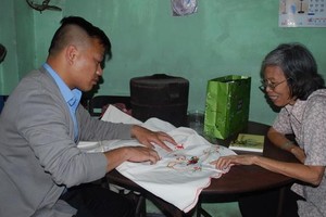 劉麗英老師（右）向作者介紹床簾上的繡花。