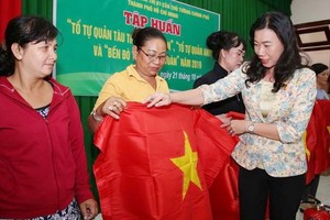 市越南祖國陣線委員會副主席趙麗慶（右一）將國旗贈予芹耶縣漁民。（圖源：勞動者報）