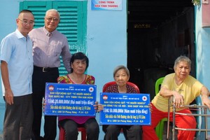 本報編委兼編輯部主任范興(左)和華企呂永雄在轉 交儀式上向戶主象徵贈送贊助修建溫情屋經費數目牌子。