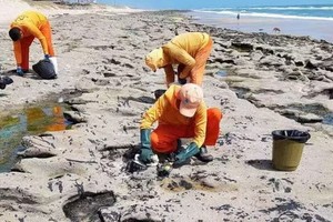 清理人員在處理沙灘表面的有毒原油。（圖源：視頻截圖）