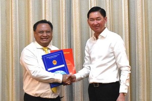 新任第十一郡人委會主席陳飛隆（左）從市人委會副主席陳永線手中接過人事委任《決定》。（圖源：VOH）