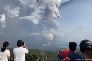 當地時間1月12日，菲律賓馬尼拉西南卡維特省的塔蓋泰鎮，民眾在給爆發的火山拍照。（圖源：AFP）