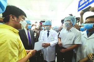 大水鑊醫院院長阮知識醫生向病人李子超(黃衣)遞交出院證。