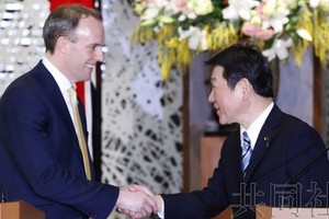 日本外相茂木敏充（右）與英國外交大臣拉布握手。（圖源：共同社）