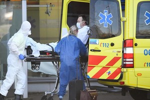 新冠疫情在荷蘭快速蔓延，救援人員送患者上救護車。（圖源：路透社）