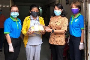 第六郡婦聯會主席梁氏菁竹(右二)向一名華人貧困者贈送禮物。