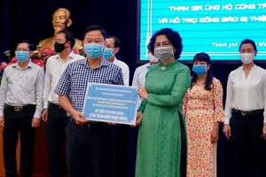 市越南祖國陣線委員會主席蘇氏碧珠接受第五郡領導的抗疫善款。