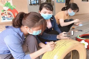 女教師們認真地在用來製成洗手盆的每一個廢舊車胎上畫圖案。