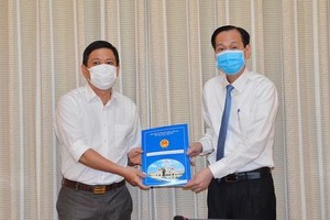 陳春田同志（左）從市人委會常務副主席黎清廉手中接過人事委任《決定》。（圖源：越勇）