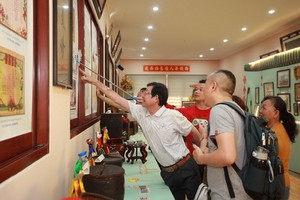 作者的叔父在“西堤華人懷舊物品展”上向觀眾介紹我家昔日的“全家福”。