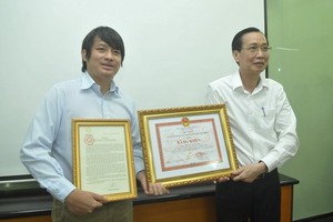 市人委會常務副主席黎清廉親自轉發表揚信和獎狀給黃俊英（左）。（圖源：高昇）