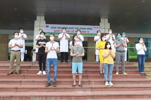 5月5日，在中央熱帶病醫院收治的11 名新冠肺炎患者痊愈出院前與醫護人員合照。（圖源：越通社）