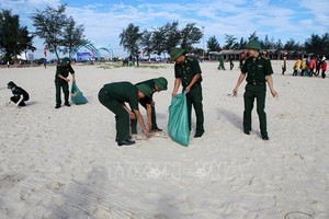 廣治省由靈縣青年官軍、士兵及共青團員在沙灘上撿拾垃圾，攜手保護環境。（圖源：越通社）
