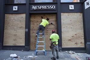 應對示威者從被砸毀的店舖，工人對一家店舖的櫥窗進行加固。（圖源：AP）