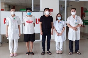 兩名新冠肺炎患者（左二、三）病癒出院前同醫護人員合照。（圖源：VOV）