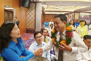 第五郡勞動聯團主席黎氏碧幸（左一）向模範勞工戴上花環祝賀。